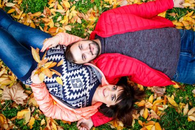 Birbirine aşık çiftler parktaki sonbahar yapraklarında dinleniyorlar. Üst görünüm.