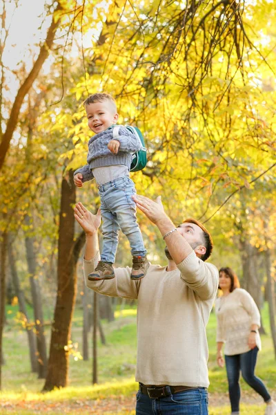 Happy family is resting in autumn park. Father joyfully throws h — Stock Photo, Image