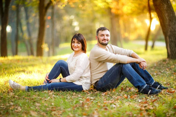 Young family and autumn concept. Couple in love sits on fallen l — Stock Photo, Image