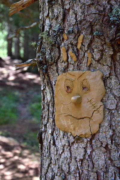 Forest spirit shaped from clay on a tree trunk - children create works of clay and attach them to the bark of a tree trunk in the forest