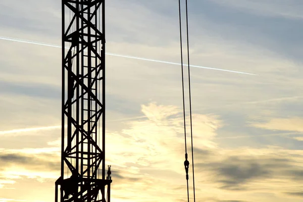 Silhouette of a construction crane at dusk - background and banner