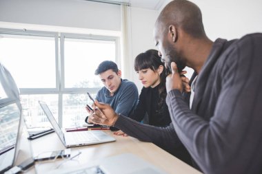 Birlikte laptop bilgisayar ve akıllı telefon kullanarak çalışma çok ırklı iş adamları