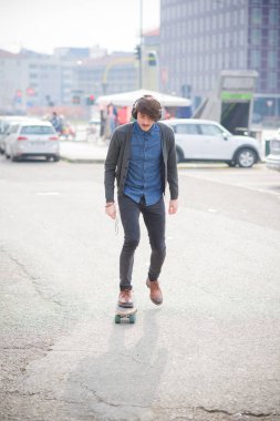 Genç yakışıklı beyaz adam tarafından kulaklık müzik sokaklarda buz pateni bıyıklı 