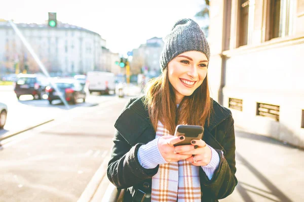 若い女性のスマート フォンを使用して 笑みを浮かべて屋外 — ストック写真