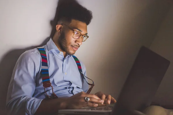 ラップトップコンピュータを使用して若い黒人男性の屋内座ってソファ リモートワーク ビジネス 技術コンセプト — ストック写真