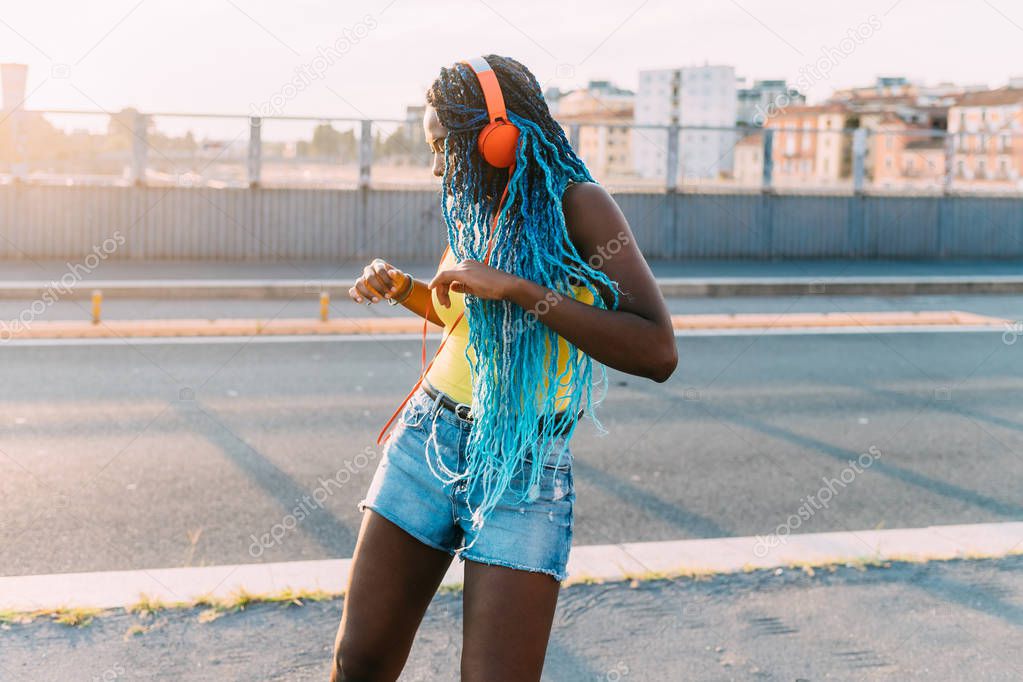 young black millennial woman outdoor listening music dancing - freedom, woman power, happiness concept