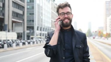 Şehirde genç sakallı Beyaz adamın telefonda konuşurken portresi 