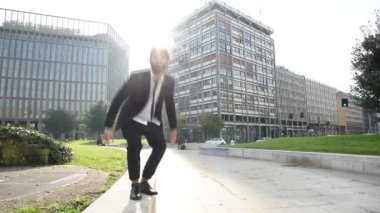 Genç yakışıklı çağdaş işadamı şehir arka ışık açık atlama