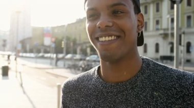 Genç yakışıklı amerikalı Afrikalı adam şehir arka ışık, kameraya bakarak gülüyor 
