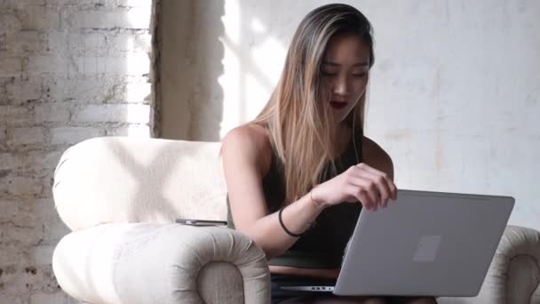 利用笔记本电脑和智能电话无线技术 无线通信 远程工作理念 使年轻女性坐在扶手椅办公室的内部 — 图库视频影像