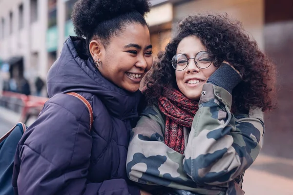 Two youg women hugging in the street — Stock Photo, Image