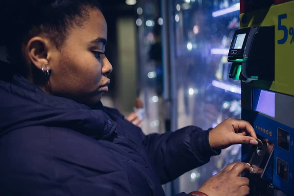 Jovem menina negra olhando máquina automática — Fotografia de Stock