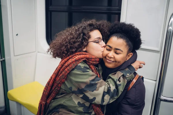 Двоє друзів цілуються в метро обіймаючись — стокове фото