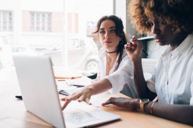 Dizüstü bilgisayarlı bir proje üzerinde çalışan iki genç kadın.