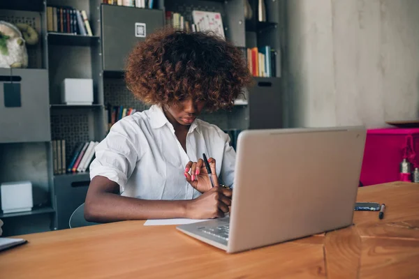 Junge schwarze Frau schreibt und benutzt Laptop — Stockfoto