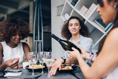 Modern kafede oturan ve birlikte içki içen genç çok ırklı kadınlar.