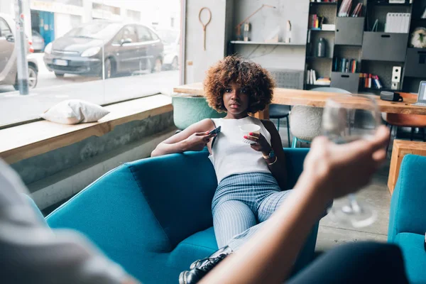 Dua wanita multirasial muda duduk di pub modern dan minum bersama — Stok Foto