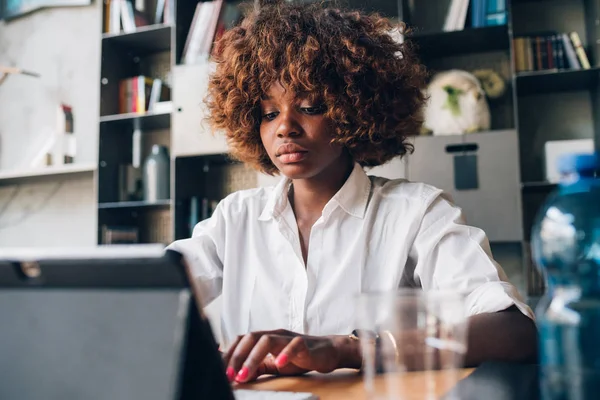 Estudiante africano joven que trabaja con la tableta en un proyecto en un estudio moderno — Foto de Stock