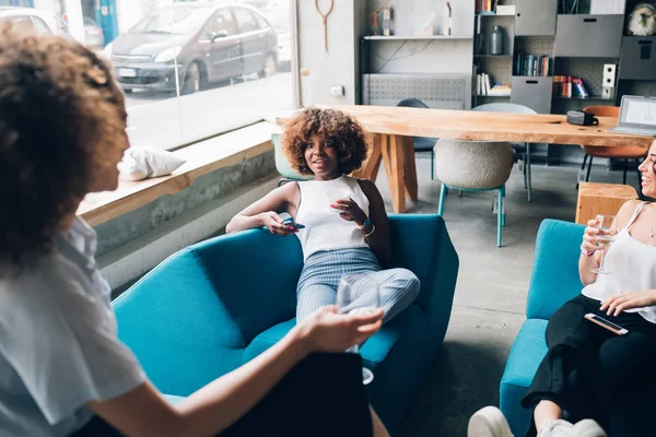 Drie jonge multiraciale vrouwen zitten in een moderne pub en drinken — Stockfoto