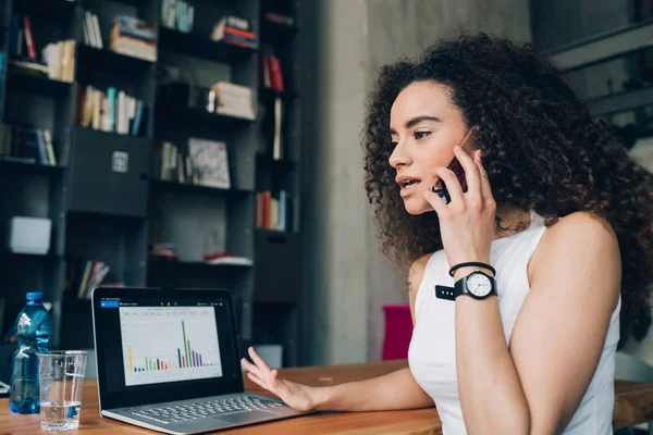 Jong brunette vrouw het hebben van business call en het werken met laptop — Stockfoto