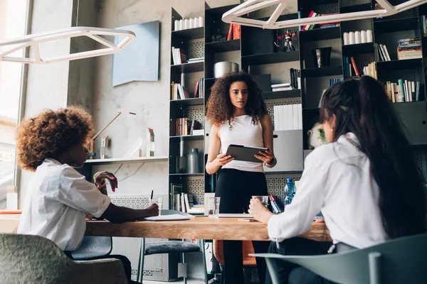 Drie jonge multiculturele zakenvrouwen praten over project in coworking — Stockfoto