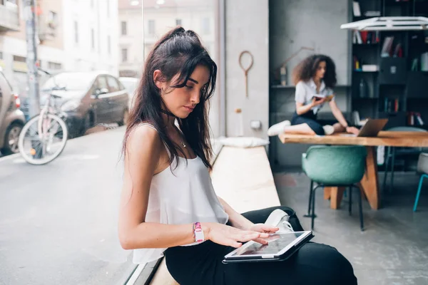 Twee jonge Kaukasische zakenvrouwen met behulp van digitale apparaat in moderne coworking office — Stockfoto