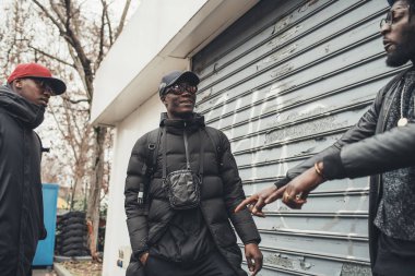 Üç Afrikalı adam sokakta dikilip sohbet ediyorlar.