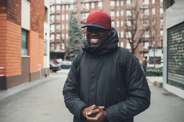 Retrato de un joven africano de pie en la calle y sonriendo — Foto de Stock