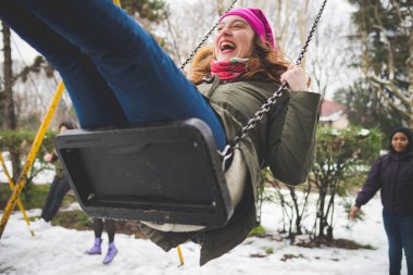 Genç mutlu kadın oyun alanında salıncakta eğleniyor. Hareket, gençlik kültürü, tatil konsepti.