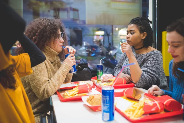 Grupp unga multirasistiska kvinnor som äter snabbmat och har samtal — Stockfoto