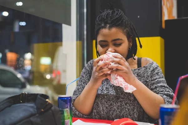 Jong Afrikaans vrouw eten sandwich indoor — Stockfoto