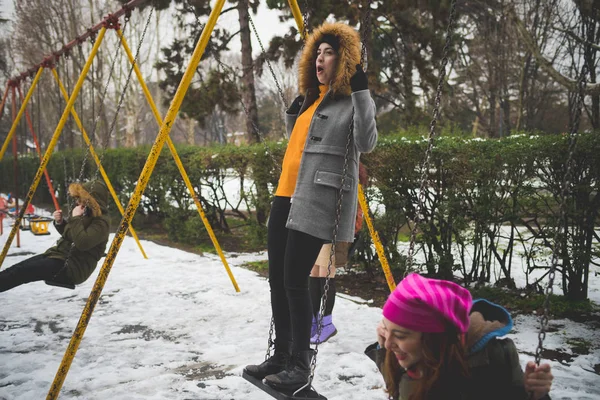 Young women having fun on the swing outdoor in winter day — Stock Photo, Image