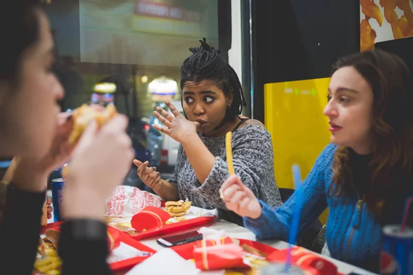 Wielorasowe dziewczyny jedzące razem w fast food — Zdjęcie stockowe