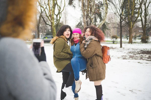 Três mulheres jovens posando para foto no parque com neve de cobertura — Fotografia de Stock