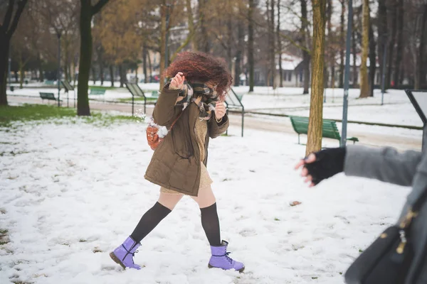 Joven mujer rizada jugando en parque con nieve —  Fotos de Stock