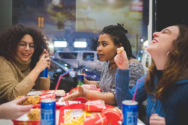 Młoda Afrykanka jedzenie kanapki z przyjaciółmi w fast food — Zdjęcie stockowe
