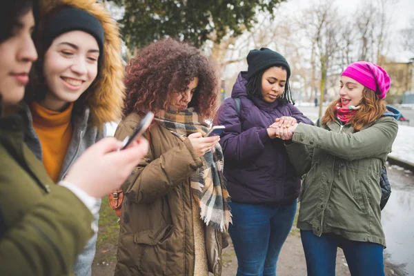 Grupo de mujeres jóvenes de pie en la calle e interactuando con el teléfono inteligente — Foto de Stock