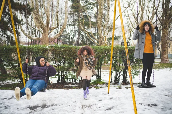 Group of young women having fun on the swing outdoor in winter day — Stock Photo, Image