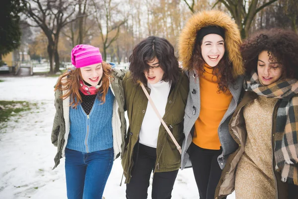 Grupp flickvänner kramas och ler i parken med snötäcke — Stockfoto