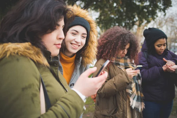 Grupo de mujeres jóvenes de pie en la calle e interactuando con —  Fotos de Stock