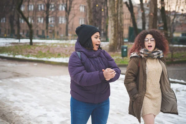 Två multiraciala unga kvinnor gå och prata på gatan — Stockfoto