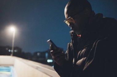 Genç Afrikalı adam akıllı telefon kullanıyor.