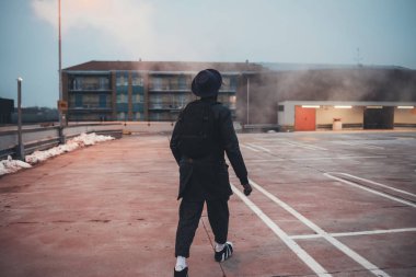 Arkaya bakan genç siyah adam sokakta yürüyor.