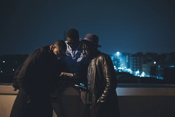 Three african friends sitting outdoor and looking the smartphone — Stock Photo, Image