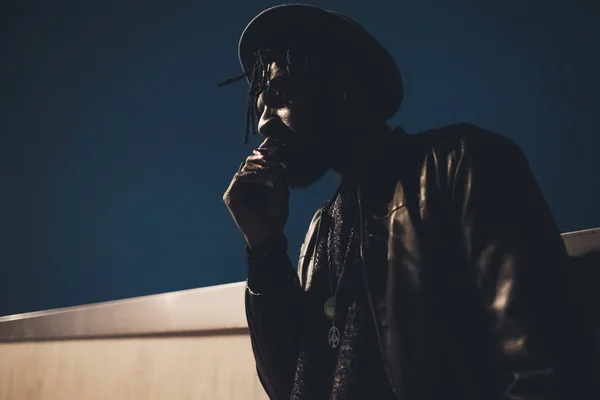 Retrato de un joven hombre negro de pie fumar cigarrillos al aire libre — Foto de Stock