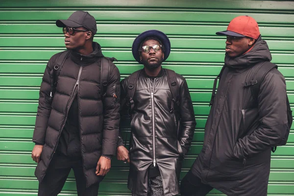 Retrato de tres jóvenes africanos apoyados contra persiana enrollable — Foto de Stock