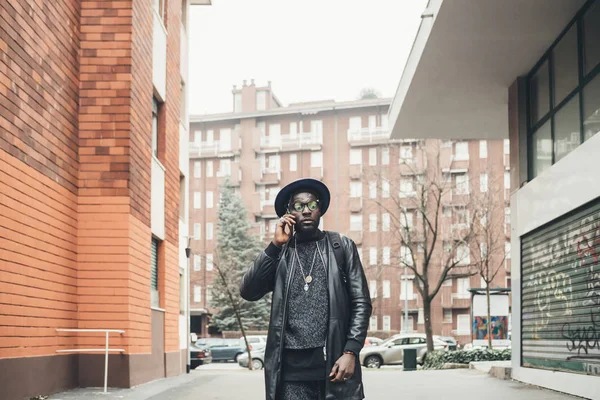 Jovem preto homem no urbano fundo falando inteligente telefone — Fotografia de Stock