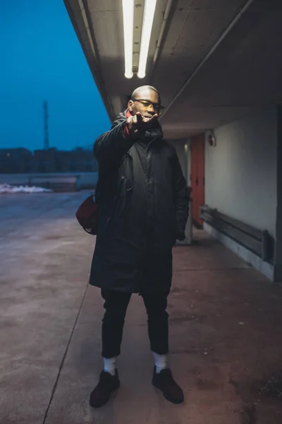 Jovem homem negro olhando câmera e posando ao ar livre — Fotografia de Stock