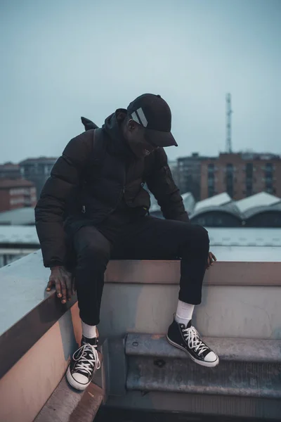 Jovem homem africano sentado no terraço rindo — Fotografia de Stock