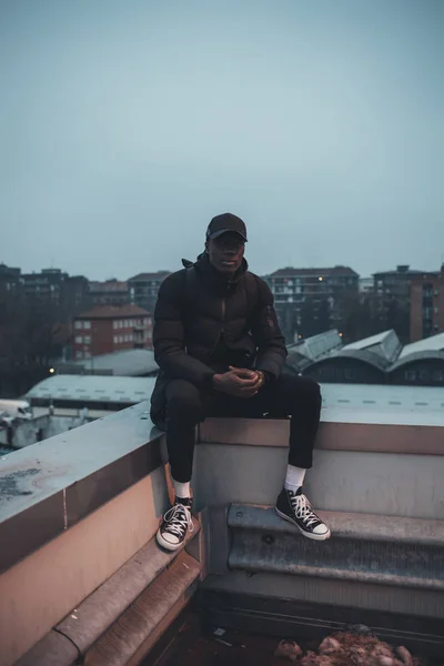 Jovem homem africano sentado no terraço e olhando câmera — Fotografia de Stock